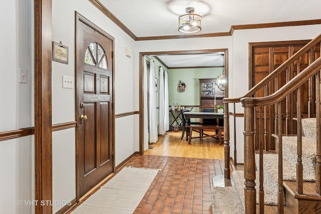 entrance foyer featuring ornamental molding, stairs, and brick floor