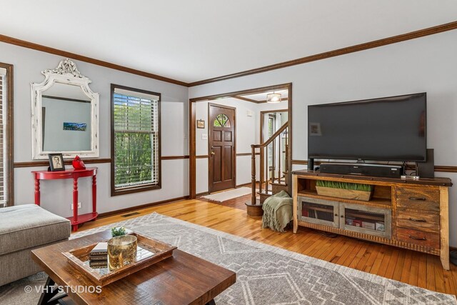 living room with stairs, visible vents, ornamental molding, and hardwood / wood-style flooring