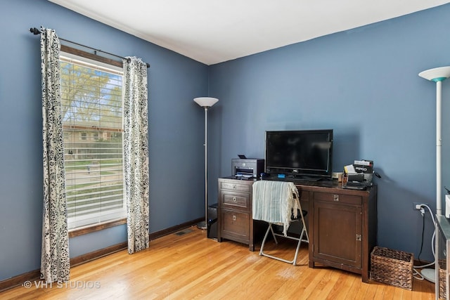 office area with baseboards, light wood-type flooring, and visible vents