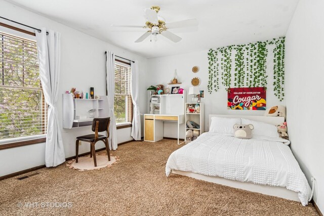 carpeted bedroom featuring a ceiling fan, baseboards, and multiple windows