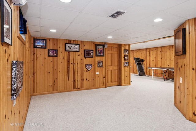 living area featuring light colored carpet, recessed lighting, visible vents, and wood walls
