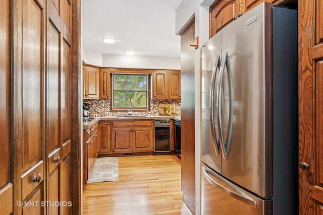 kitchen with freestanding refrigerator, brown cabinets, a sink, and light wood finished floors