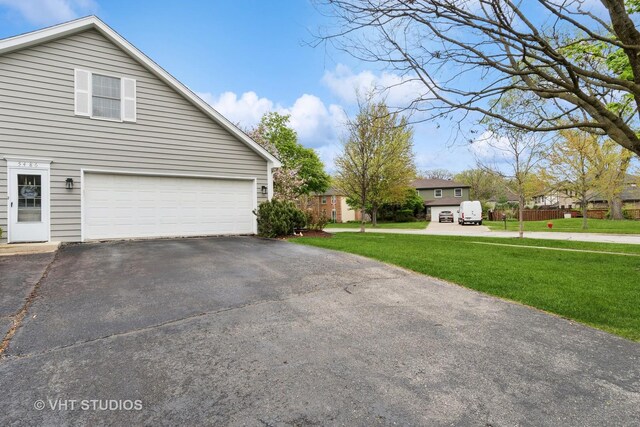 view of home's exterior with an attached garage, a yard, and aphalt driveway