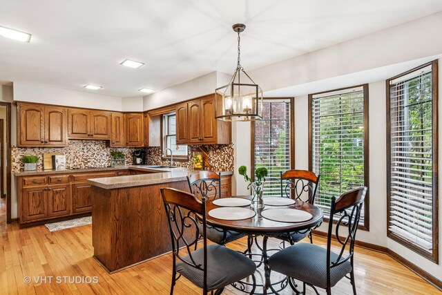 kitchen with a peninsula, a chandelier, brown cabinets, tasteful backsplash, and light wood-style flooring