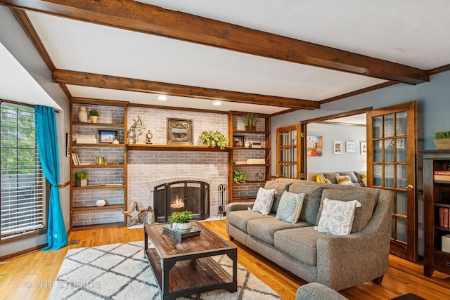 living room with a brick fireplace, beam ceiling, and wood finished floors