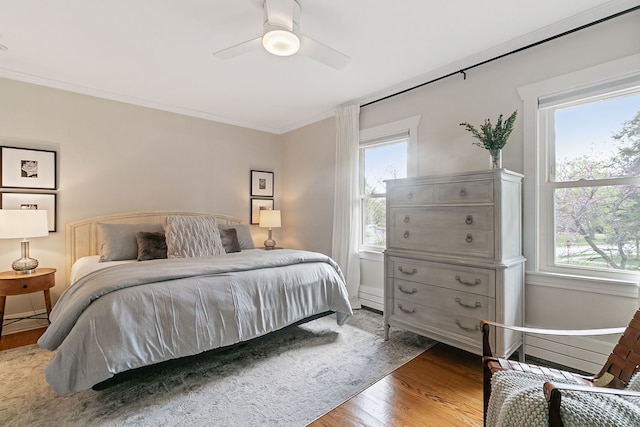 bedroom with ceiling fan, baseboards, ornamental molding, and wood finished floors