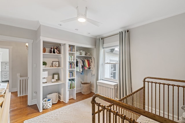 bedroom with crown molding, a nursery area, light wood-style flooring, and a closet