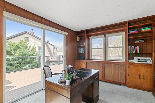 office area featuring light colored carpet, wood walls, and built in features