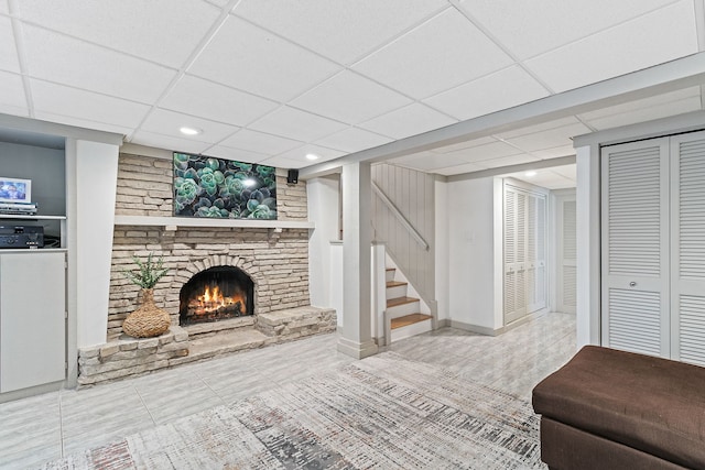 unfurnished living room featuring tile patterned flooring, a stone fireplace, stairway, recessed lighting, and a paneled ceiling