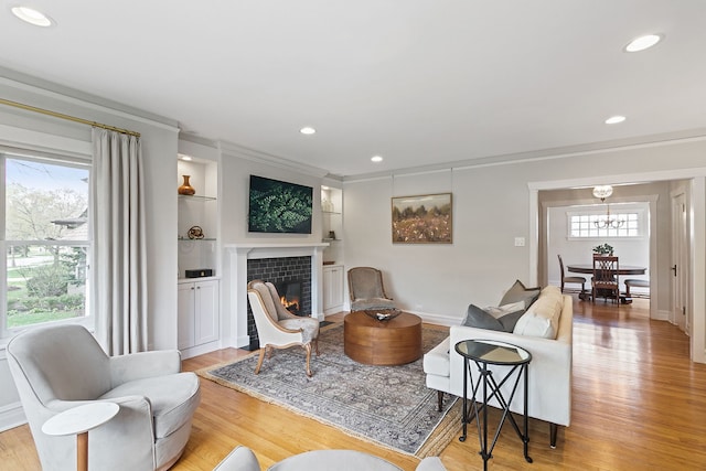 living area with recessed lighting, an inviting chandelier, a tile fireplace, and light wood-type flooring