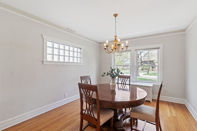 dining space with crown molding, an inviting chandelier, a wealth of natural light, and light wood-style floors