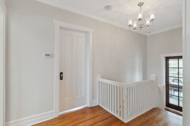 interior space featuring a notable chandelier, ornamental molding, and wood finished floors