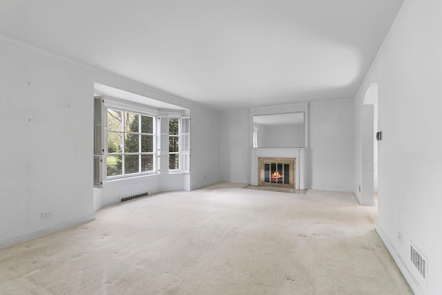 unfurnished living room with arched walkways, visible vents, a fireplace with flush hearth, and carpet