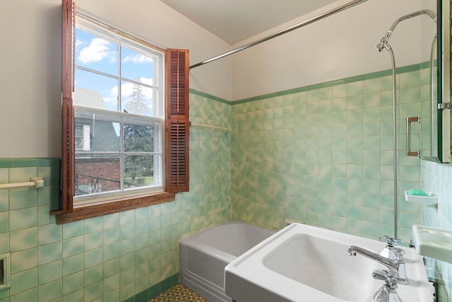 bathroom featuring tile walls, a sink, and a bath