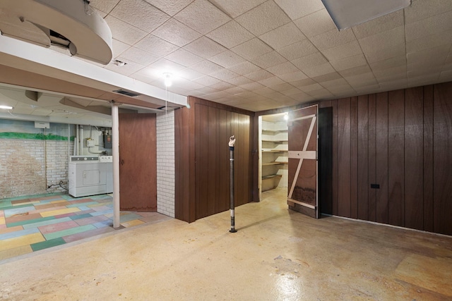 finished basement with washer and dryer, wood walls, and visible vents