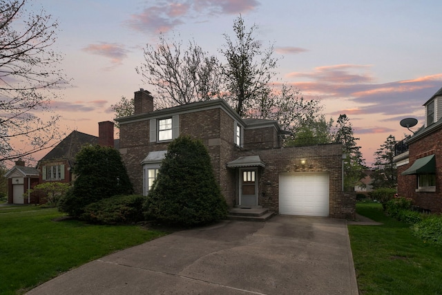 view of front of property featuring a garage, driveway, a chimney, brick siding, and a yard