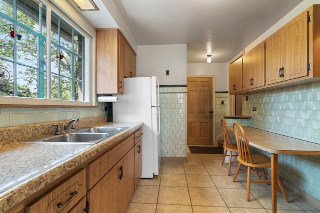 kitchen featuring a sink, light tile patterned floors, freestanding refrigerator, and light countertops