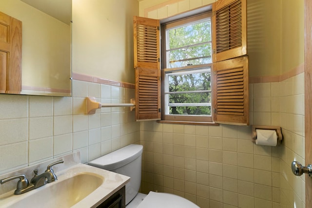 half bath featuring plenty of natural light, vanity, toilet, and tile walls