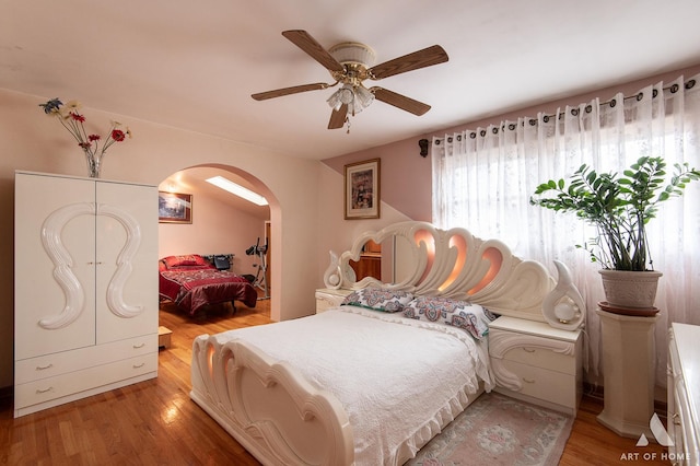 bedroom with arched walkways, ceiling fan, and light wood-type flooring