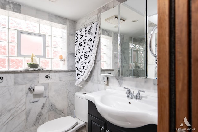 bathroom featuring tile walls, toilet, and vanity