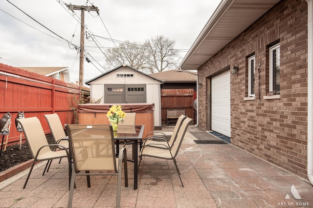 view of patio featuring outdoor dining space, a fenced backyard, and a hot tub
