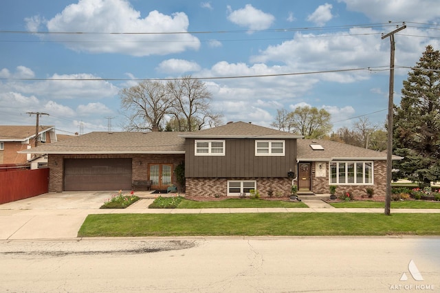 split level home with a front lawn, driveway, brick siding, an attached garage, and fence