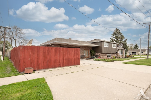 view of front of property featuring driveway, fence, brick siding, and a garage