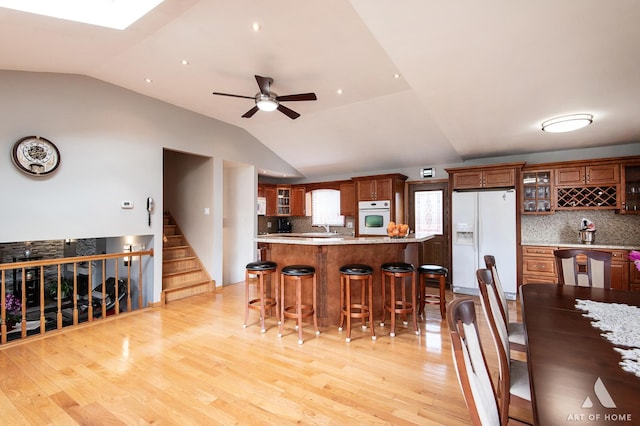 kitchen with tasteful backsplash, white appliances, ceiling fan, and vaulted ceiling