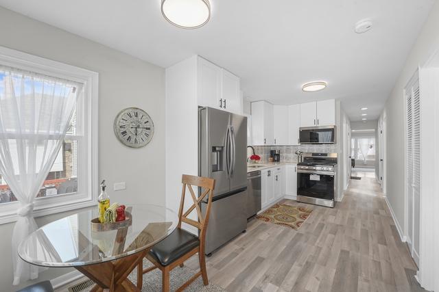 2716 N 73rd Ave, Elmwood Park, IL 60707 - kitchen featuring stainless steel appliances, a sink, light wood-type flooring, white cabinetry, and decorative backsplash