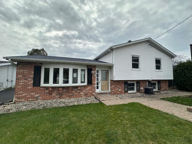 split level home with brick siding, a front lawn, and central air condition unit