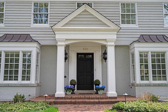 doorway to property featuring brick siding, metal roof, and a standing seam roof