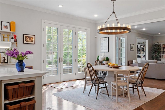 dining room featuring french doors, crown molding, wood finished floors, a notable chandelier, and recessed lighting