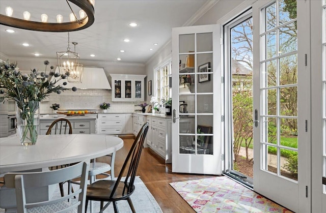 dining space featuring crown molding, a notable chandelier, recessed lighting, and dark wood-type flooring