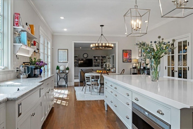kitchen featuring hanging light fixtures, dark wood-style floors, a notable chandelier, ornamental molding, and white cabinetry