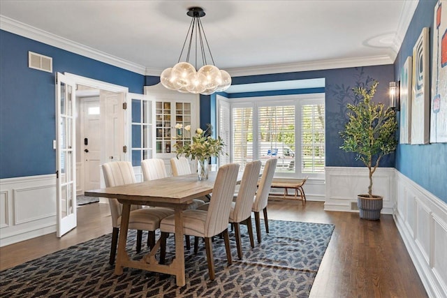 dining area with visible vents, dark wood finished floors, a wainscoted wall, and an inviting chandelier