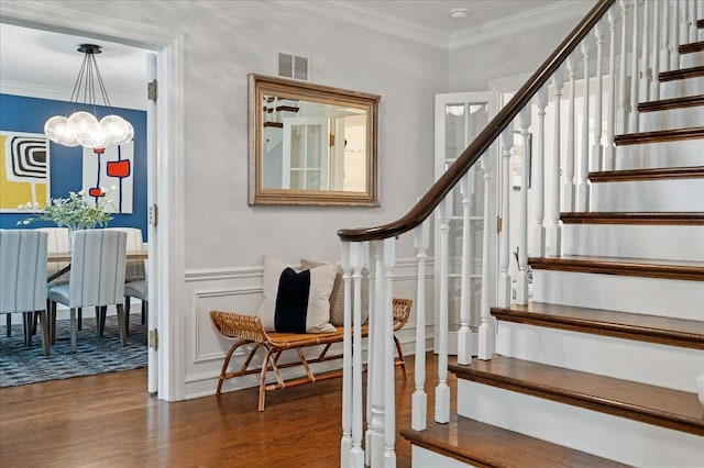 staircase with visible vents, ornamental molding, wood finished floors, and a chandelier