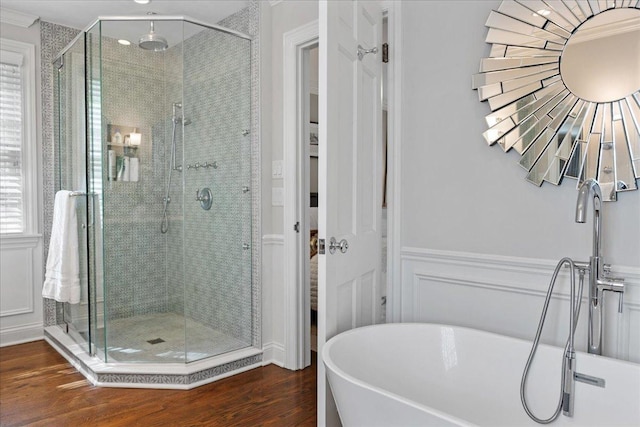 bathroom with a freestanding tub, a wainscoted wall, a shower stall, and wood finished floors