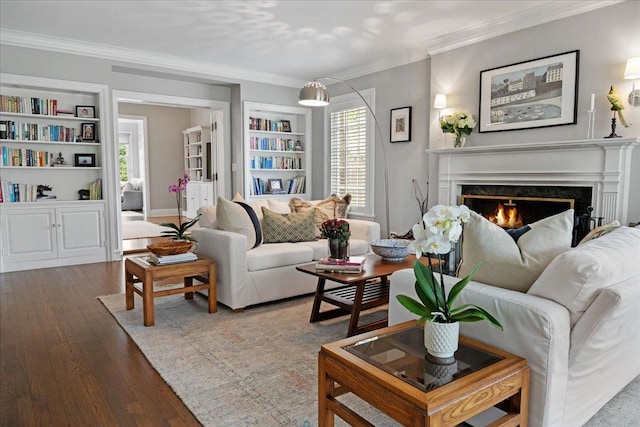 living room featuring crown molding, built in features, wood finished floors, and a healthy amount of sunlight