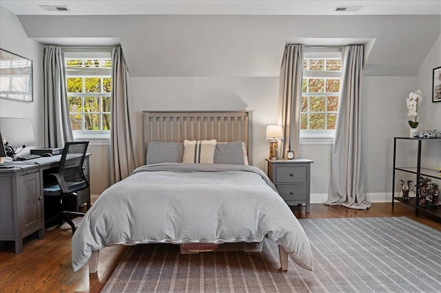 bedroom featuring visible vents, lofted ceiling, multiple windows, and wood finished floors