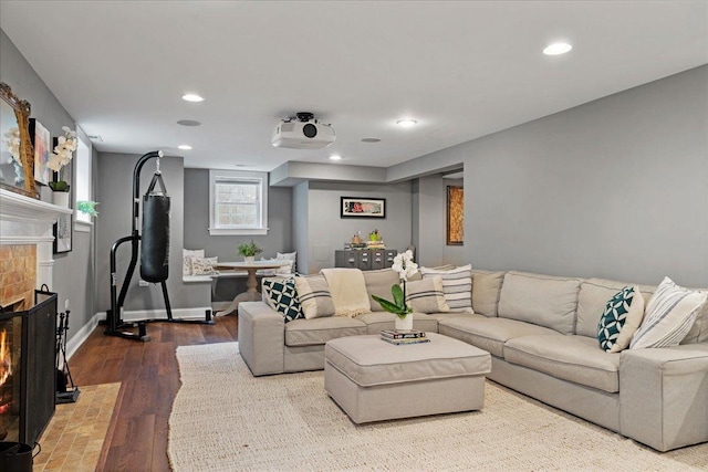 living area featuring recessed lighting, a fireplace with flush hearth, baseboards, and wood finished floors