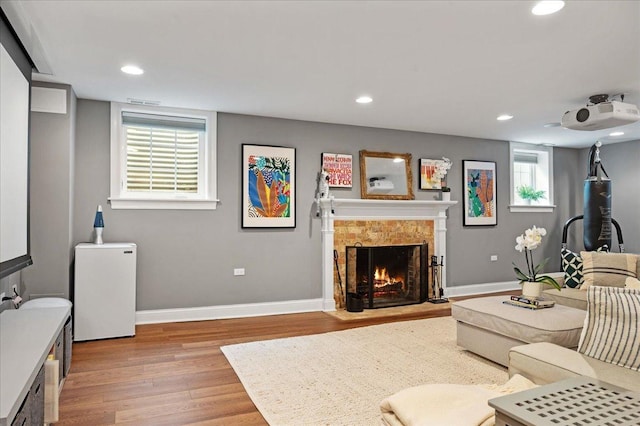 living room featuring a fireplace, recessed lighting, baseboards, and light wood-style floors