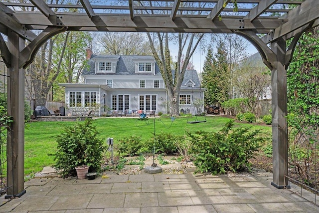 back of house with a lawn, a patio area, and a chimney