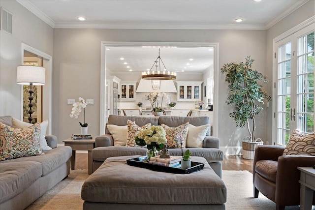 living area with an inviting chandelier, visible vents, ornamental molding, recessed lighting, and light wood-type flooring