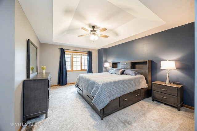 bedroom featuring baseboards, ceiling fan, a tray ceiling, and light colored carpet