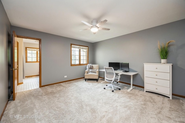 carpeted office space featuring baseboards, a ceiling fan, and a wealth of natural light