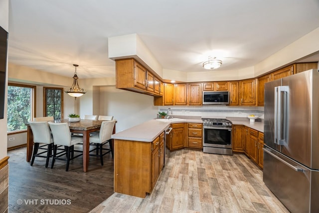 kitchen featuring brown cabinetry, a sink, light wood-style floors, and stainless steel appliances