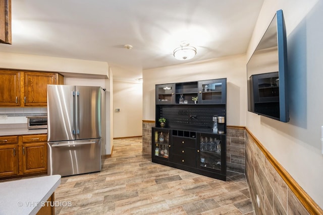 kitchen featuring brown cabinets, a toaster, light countertops, freestanding refrigerator, and light wood finished floors