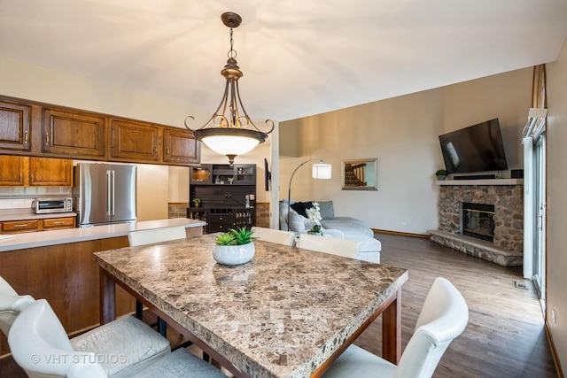 kitchen featuring freestanding refrigerator, wood finished floors, a toaster, a breakfast bar, and open floor plan