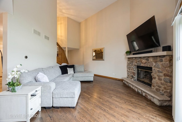 living room with visible vents, wood finished floors, a fireplace, and stairway