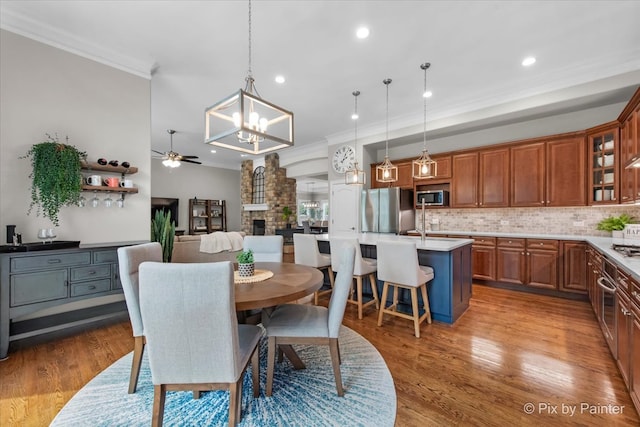 dining space with light wood-style floors, ornamental molding, ceiling fan with notable chandelier, and recessed lighting